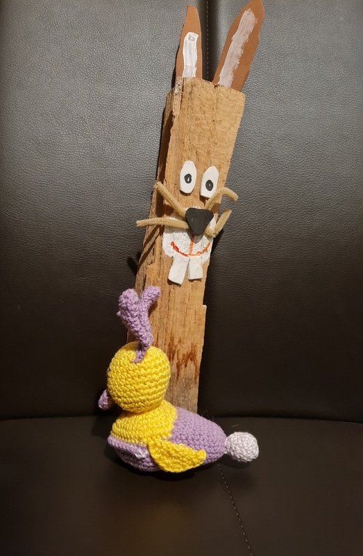 Kleiner gehäkelter Amigurumi‑Vogel in Gelb und Lila mit sichtbarer Maschenstruktur