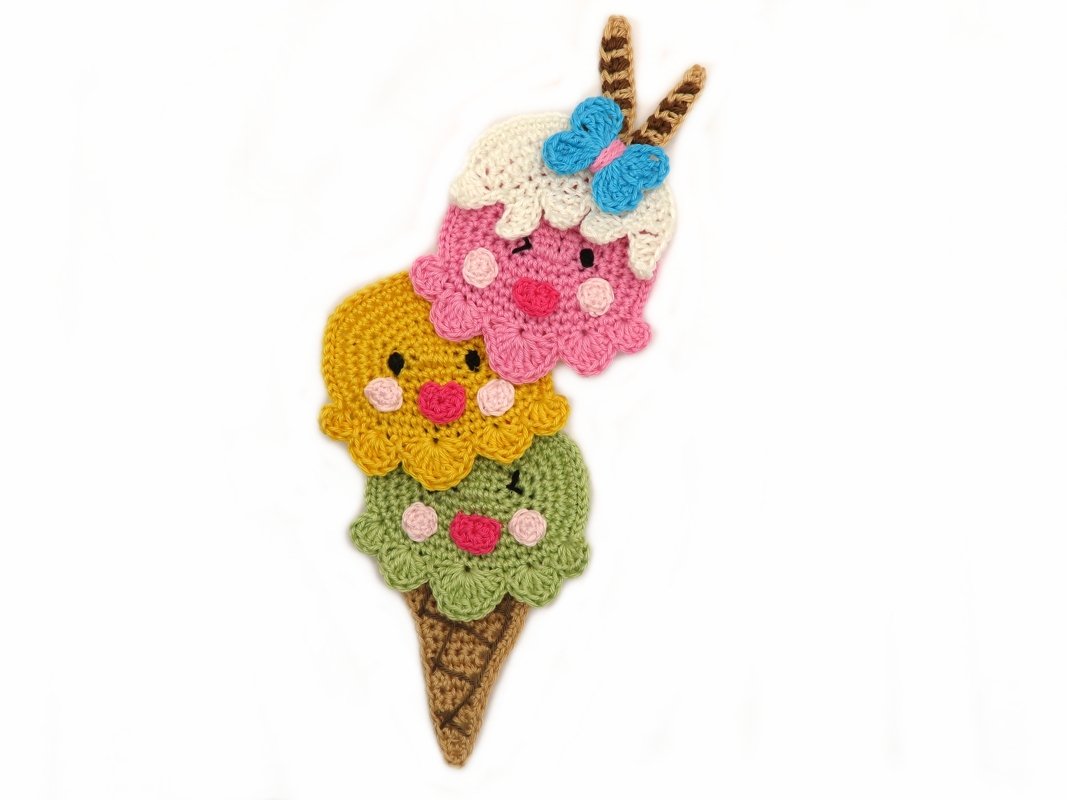 Whimsical crochet ice cream appliqué with smiling faces, blue bow and cone