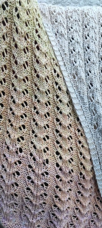 Nahaufnahme des Blatt‑Lochmusters an zwei gestrickten Tüchern in unterschiedlichen Farbnuancen