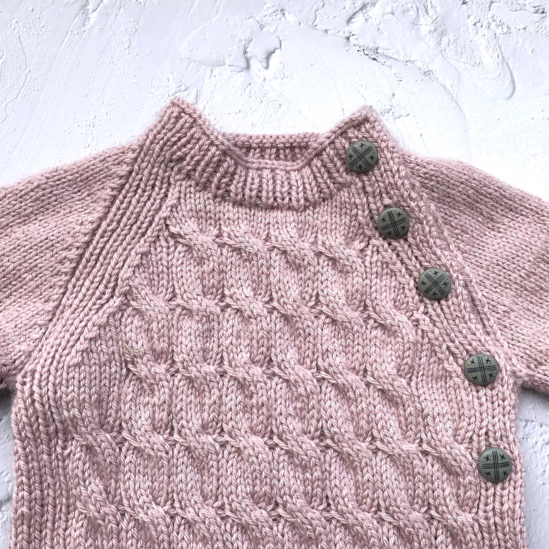Rosa gestrickter Baby-Pullover mit Zopfmuster und Schulterknöpfe