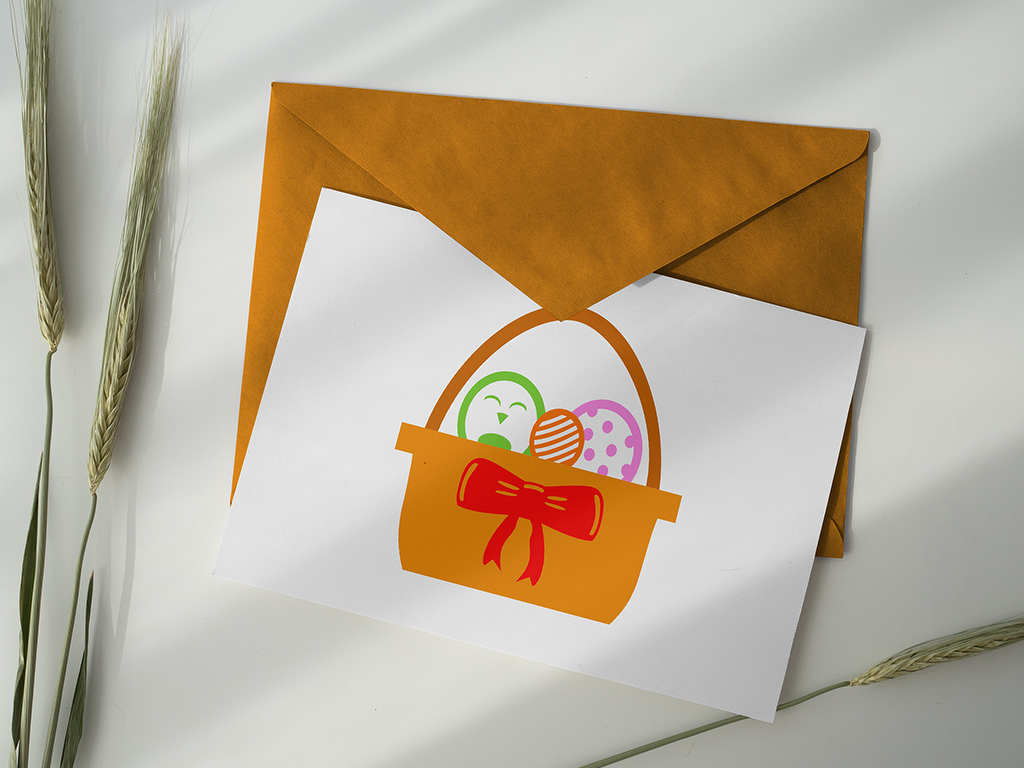 Weiße Karte in braunem Umschlag mit orangefarbenem Osterkorb, roter Schleife und drei bunten Ostereiern