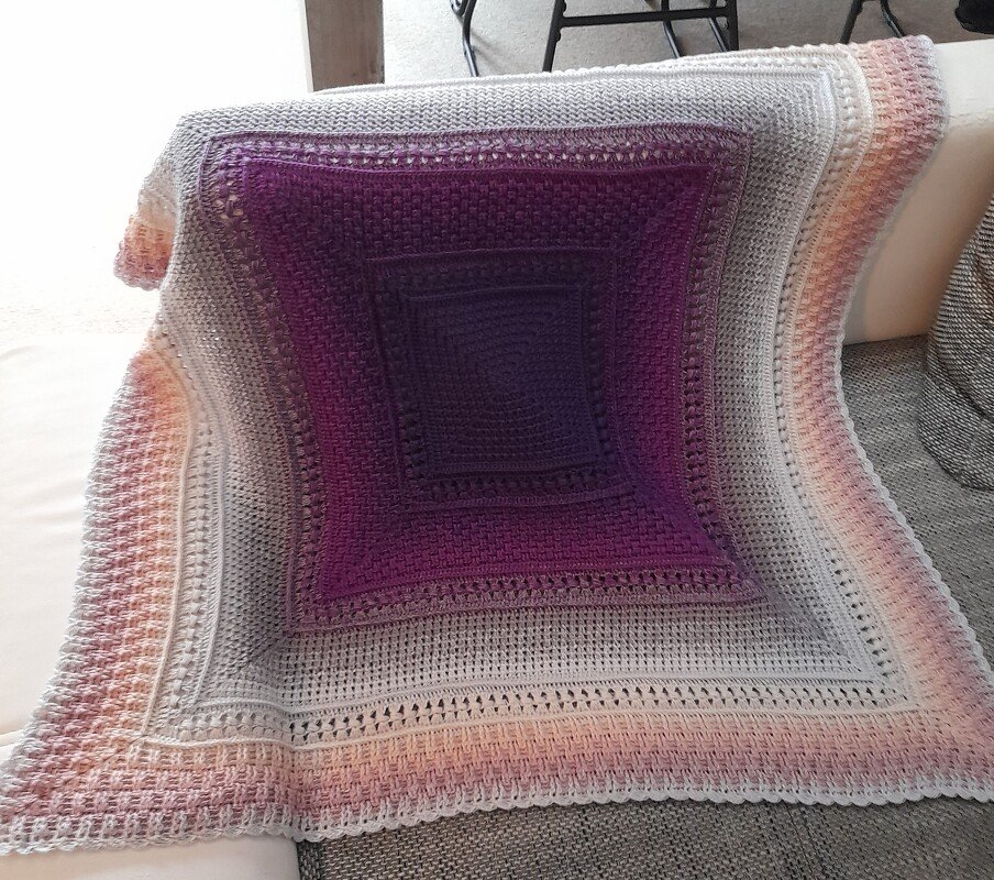 Gehäkelte Decke in Lila, Grau und Rosa mit Farbverlauf und Quadratmuster auf Sofa
