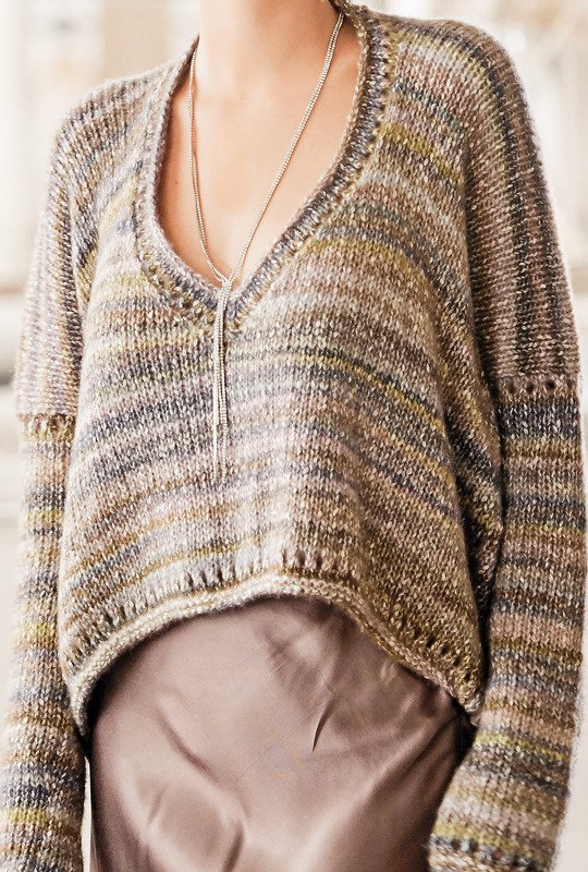 V-Ausschnitt-Strickpullover aus meliertem Garn in Braun-, Grau- und Grüntönen mit langer silberner Kette, Nahaufnahme bis zur Taille.