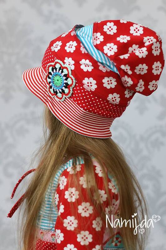 Rote genähte Kindermütze mit Schirm, Blumen-, Punkte- und Streifenmustern sowie Häkelblume, Seitenansicht
