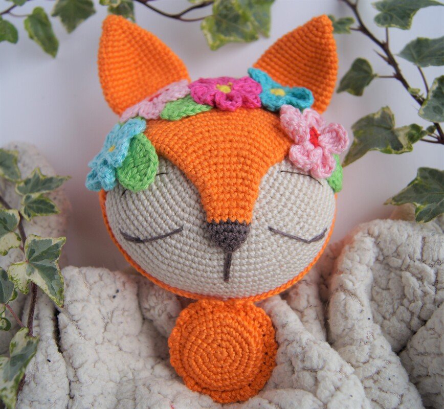 Gehäkelter orange-weißer Fuchs mit Blumenkranz und geschlossenen Augen