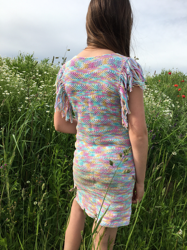 Back view of a child wearing a straight-fit pastel variegated knitted dress with short fringe sleeves