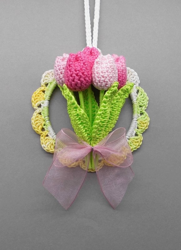 Crocheted hanging ornament with pink tulips, green leaves, scalloped yellow-green ring and sheer pink bow.