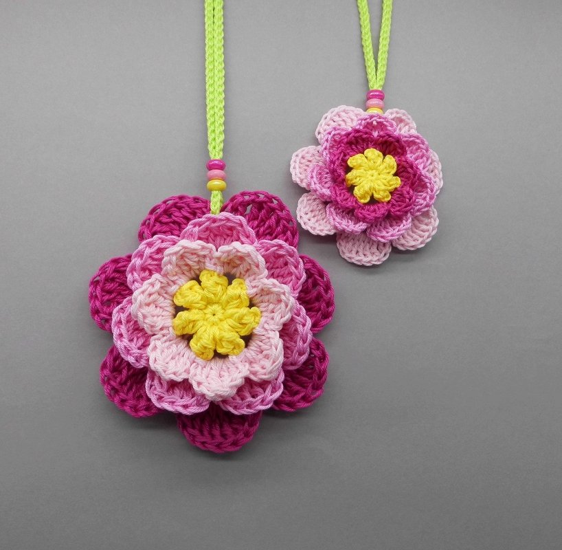 Two layered pink crochet flowers with yellow centers and bead-adorned neon cords, suitable for Mother's Day decor