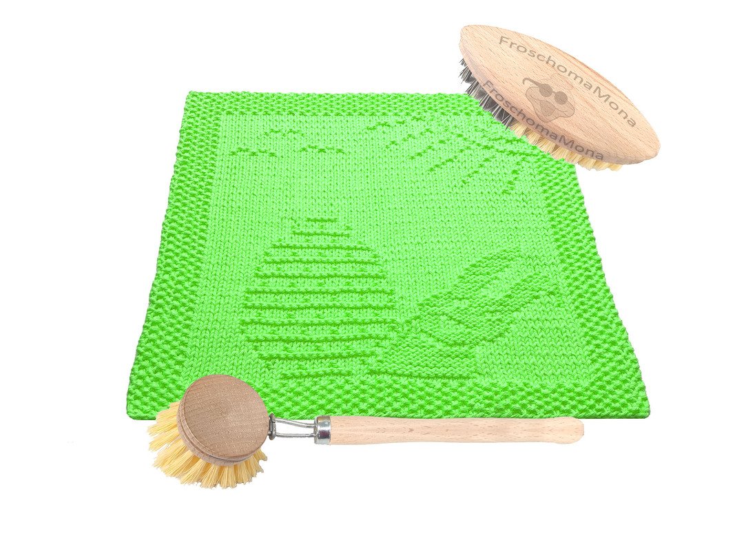 Grünes gestricktes Spültuch mit Osterei- und Blattmuster neben zwei Holzspülbürsten
