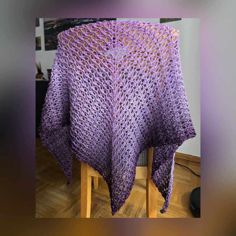 Lila verlaufendes gehäkeltes Dreieckstuch mit offenem Lochmuster, über einem Stuhl drapiert