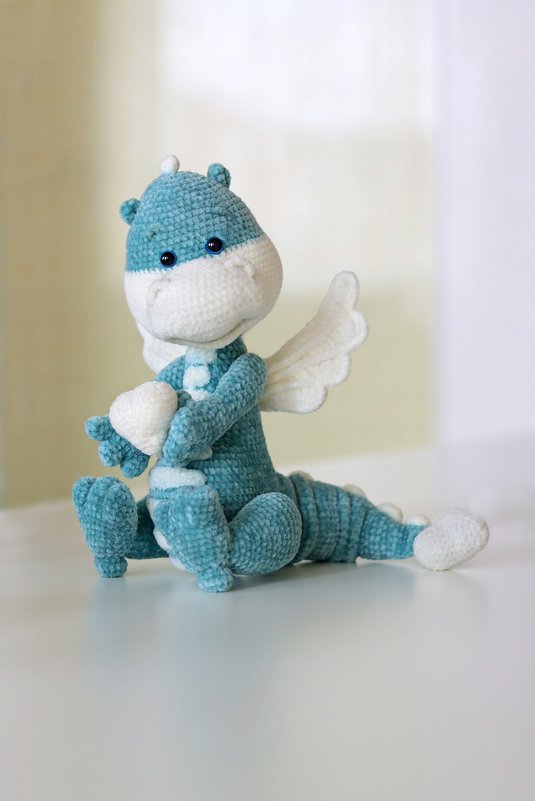 Gehäkelter türkis‑weißer Amigurumi‑Drache mit Flügeln und Herz