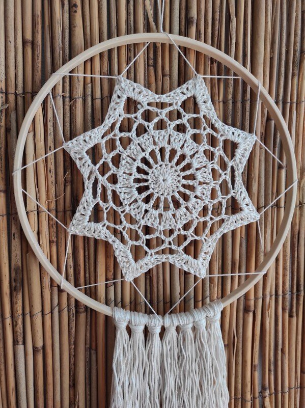 weiß gehäkelter Stern im Holzring mit Fransen vor Bambus