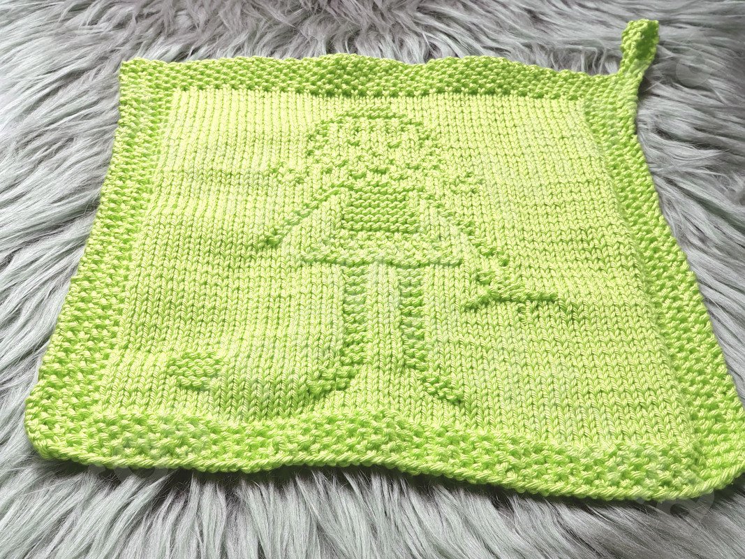 Hellgrünes gestricktes Quadrat mit Pilzrelief, kraus-rechtem Rand und Aufhängeschlaufe