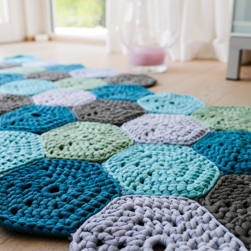 Nahaufnahme verbundener gehäkelter Motive in Türkis, Blau und Grau mit Fokus auf Struktur und Nahtstellen