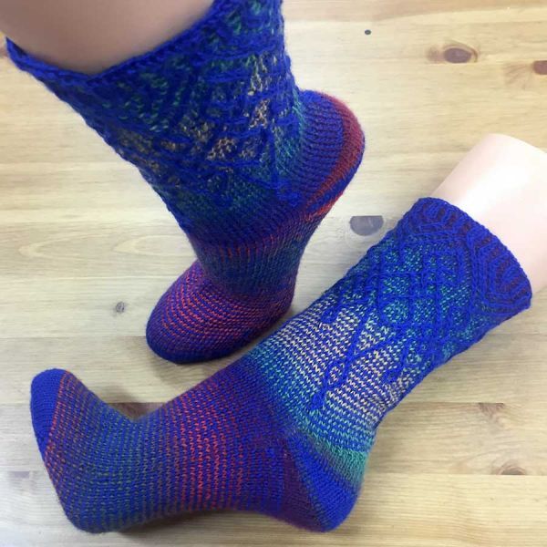 Pair of blue-to-purple gradient knitted mid-calf socks with lace leg pattern on mannequin feet