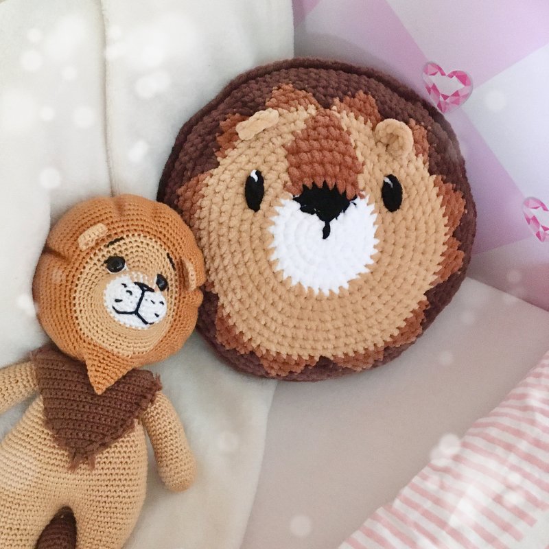 Gehäkeltes Löwenkissen neben Amigurumi-Löwenpuppe auf Bettwäsche