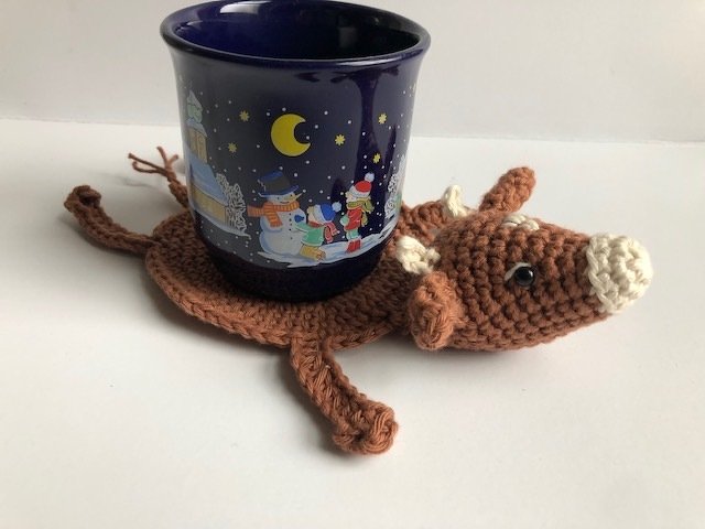 Brauner gehäkelter Rentier-Untersetzer mit blauer Tasse und Wintermotiv