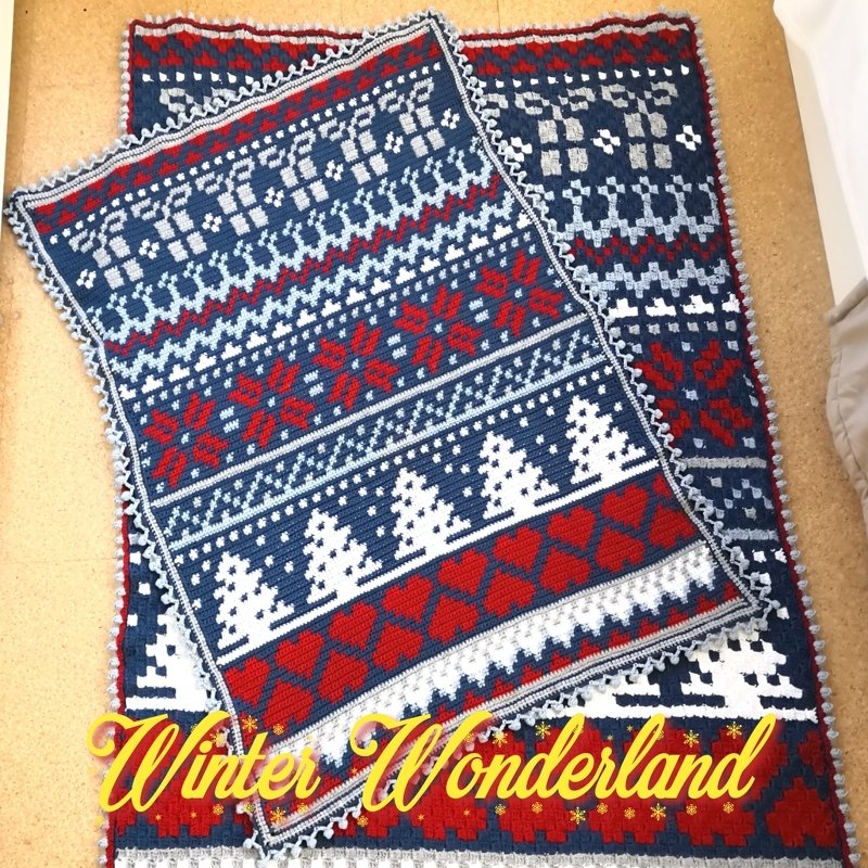 Zwei übereinandergelegte gehäkelte Decken mit blau‑rot‑weißem Wintermuster, Schneeflocken und Tannenbäumen