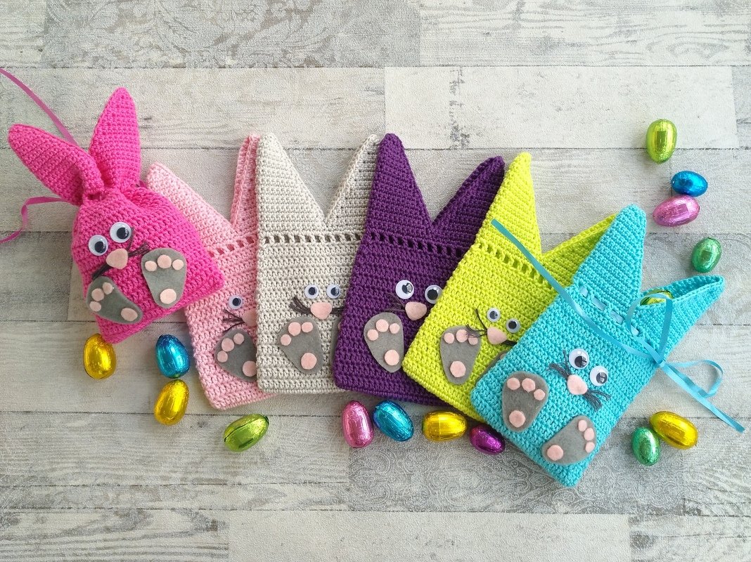 Sechs gehäkelte Häschen-Ostertaschen in leuchtenden Farben mit Ohren, Filzpfoten und Wackelaugen.