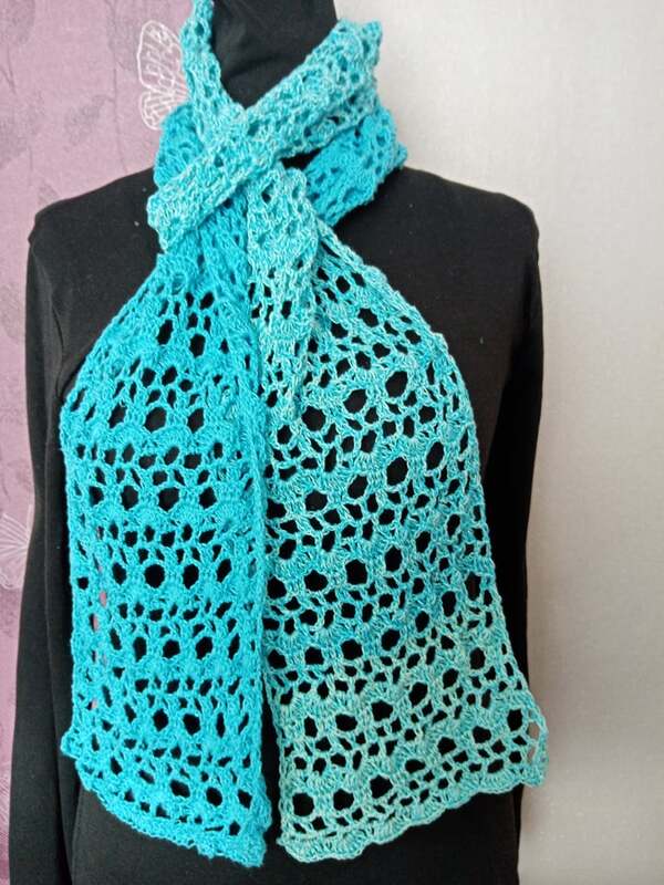 Türkisfarbener gehäkelter Schal mit durchbrochenem Lochmuster auf schwarzer Schaufensterpuppe