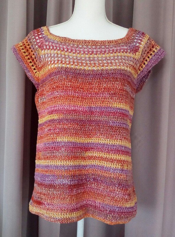 Gehäkeltes Damen-Shirt mit kurzen Ärmeln und bunten Streifen (Orange, Pink, Gelb, Lila) auf einer Schneiderpuppe.