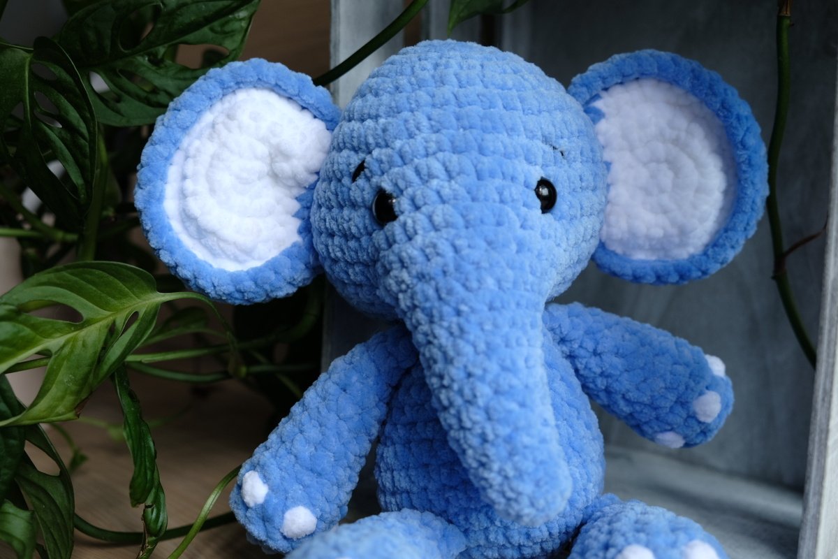 Gehäkelter blauer Amigurumi‑Elefant mit weißen Innenohren und langem Rüssel
