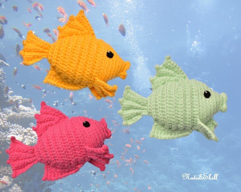 Three crocheted amigurumi fish in orange, pink, and light green against an underwater background
