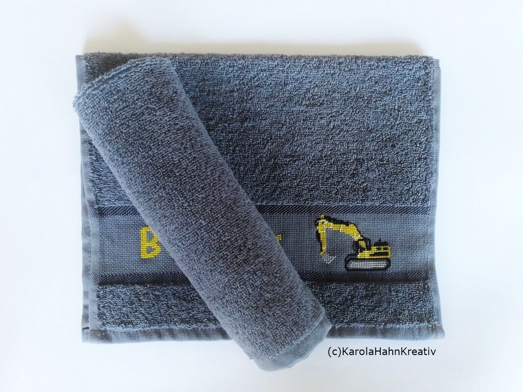 Graues Frotteehandtuch mit bestickter Zierborte: gelbes Baggermotiv und Initiale B im Kreuzstich.