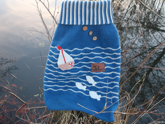 Blauer gehäkelter Babysack mit gestreiftem Umschlagkragen, Holzknöpfen, Segelboot und Fischen
