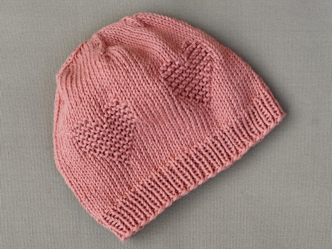 Einfach gestrickte rosa Babymütze mit Rippbündchen und Herzmuster