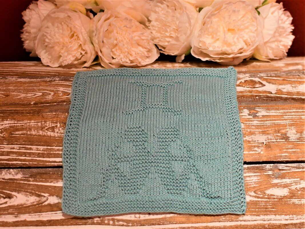 Helltürkis gestricktes Quadrat mit Rand und eingestricktem Motiv zweier Figuren