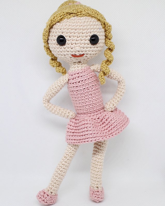 Gehäkelte Puppe mit rosa Kleid, goldblonden Zöpfen und schwarzen Augen