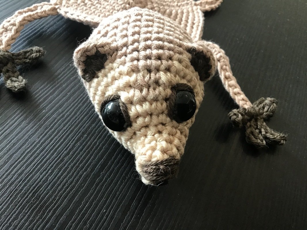 Nahaufnahme einer naturfarbenen gehäkelten Dekofigur mit schwarzen Augen