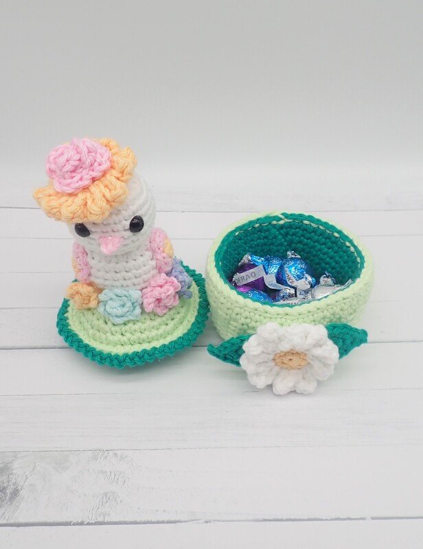 Pastel crocheted bird lid and round crochet bowl with white daisy, filled with wrapped candies