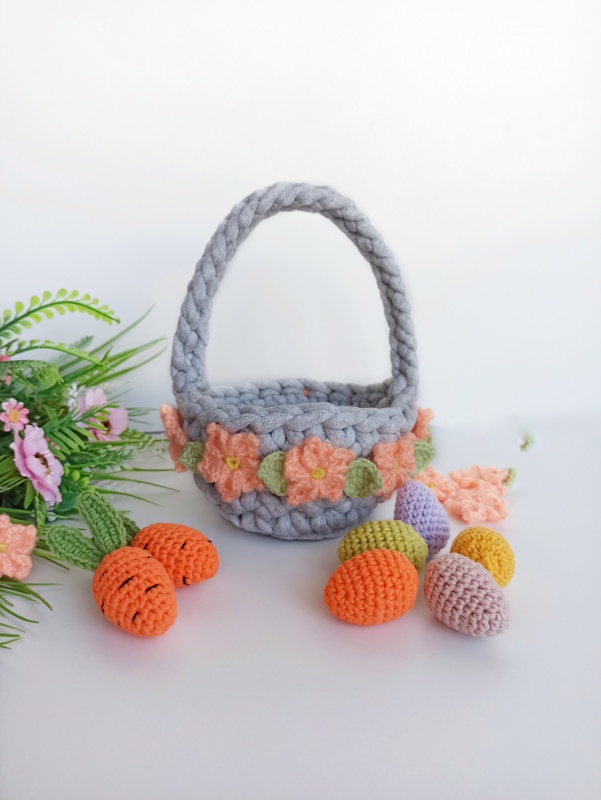 Gray crocheted basket with braided handle, peach flower trim, pastel crocheted eggs and small crocheted carrots
