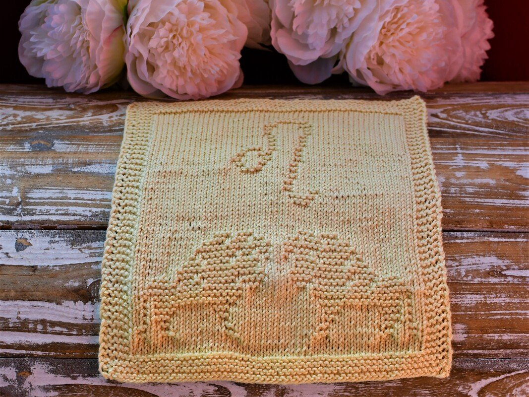 Quadratisches gestricktes Tuch in Pastellgelb mit eingestrickter Zahl 21 und Tortenmotiv
