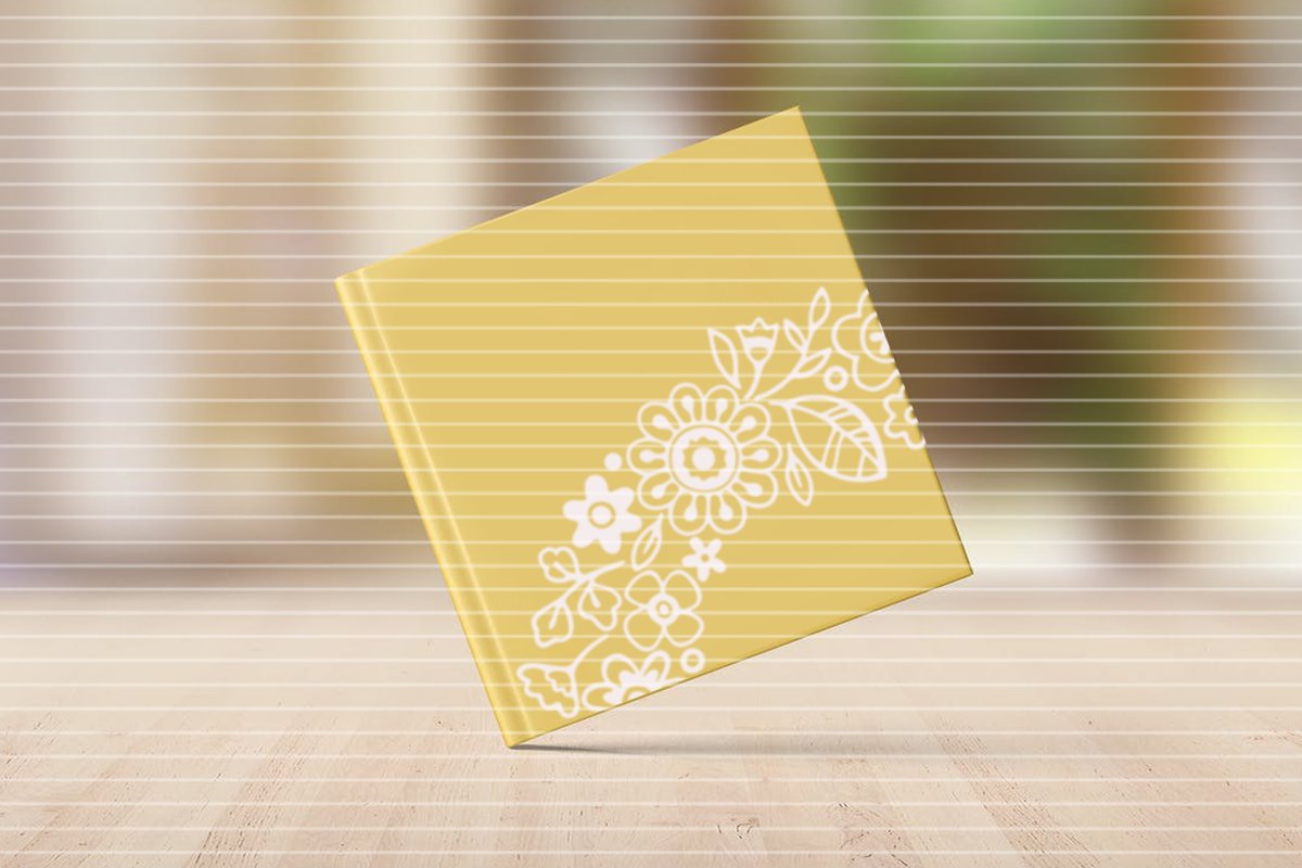 Gelbes Cover mit weißem floralen Motiv und horizontalen Streifen, vor einer Holzoberfläche