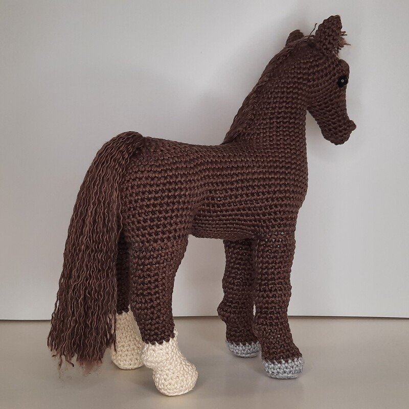 Gehäkeltes braunes Amigurumi-Pferd mit langem Schweif und zweifarbigen Hufen