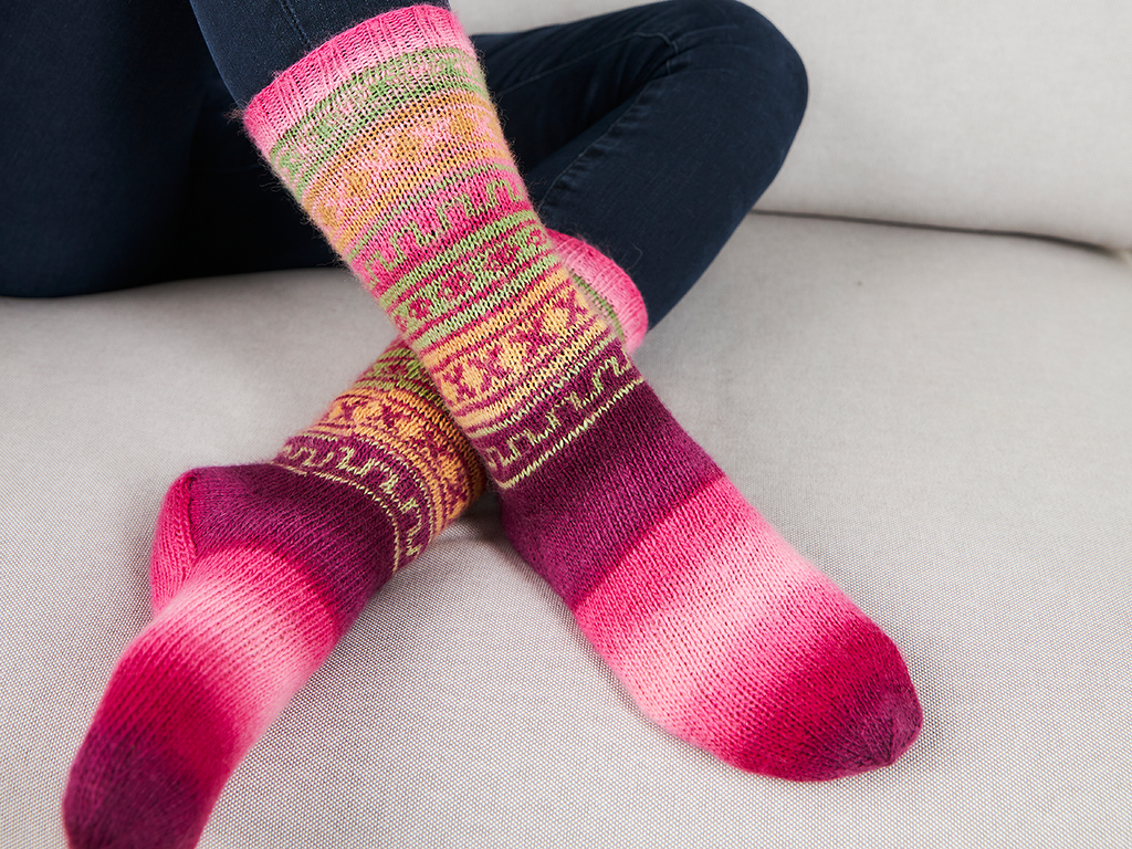 Nahaufnahme gestrickter Damensocken mit abgestuftem Farbverlauf und Ornamentstreifen