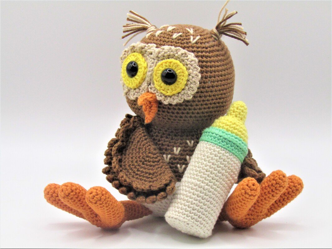 Gehäkelte braune Amigurumi-Eule mit gelber Augenpartie und Babyflasche