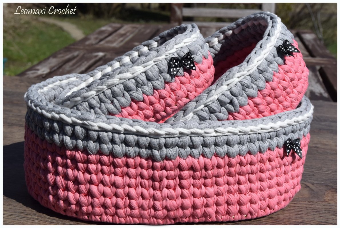 Zwei verschachtelte Häkelkörbe in Rosa und Grau mit weißer Kante und gepunkteten Schleifen