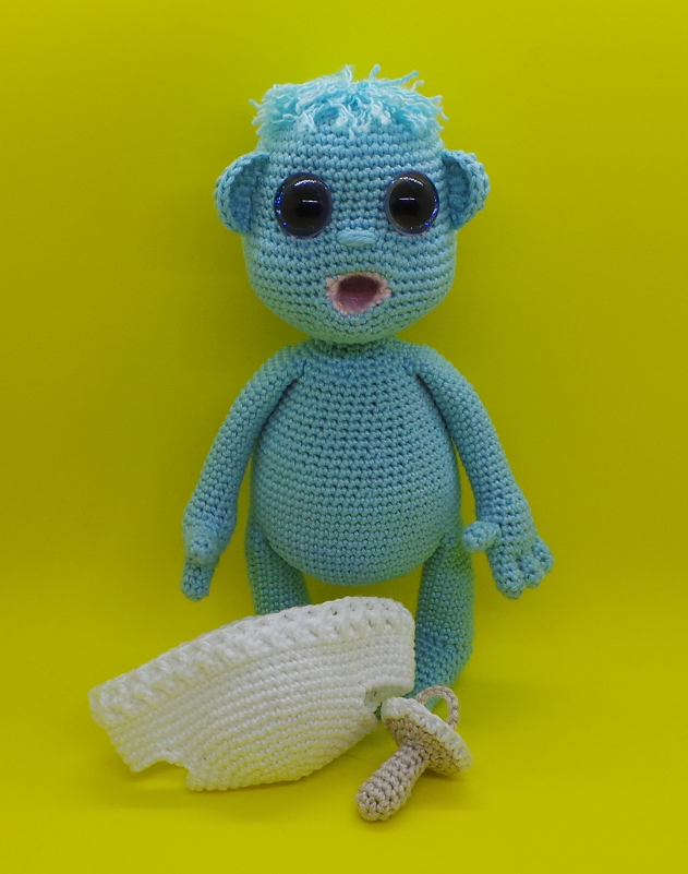 Türkises Amigurumi mit großen Augen, Schnuller und weißem Häkelteil