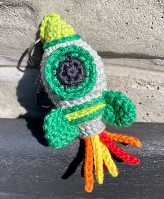 Gehäkelter Raketen‑Schlüsselanhänger mit bunten Garnflammen und Metallring