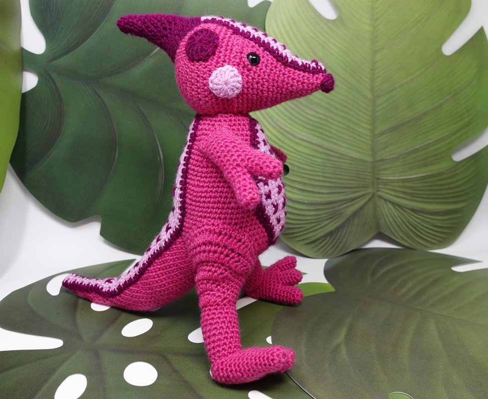 Nahaufnahme eines pink-lila gehäkelten Parasaurolophus mit sichtbaren Maschen und Kopfkamm
