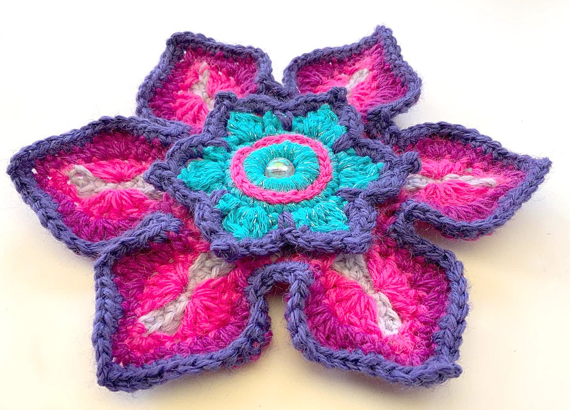 Gehäkelte Blumen-Applikation in Pink, Lila und Türkis mit Perle in der Mitte