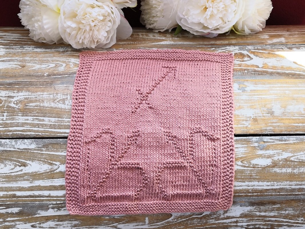 Zartes altrosa Strickpanel mit reliefierten Mustern und krausgestricktem Rand auf Holzuntergrund, weiße Blumen im Hintergrund