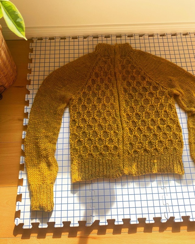 Raglan-Strickjacke in Senfgelb mit Wabenzopfmuster auf Blockiermatte