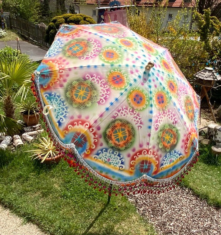 Boho-Sonnenschirm mit bunten Mandala-Mustern und gehäkelter Borte über Rasen