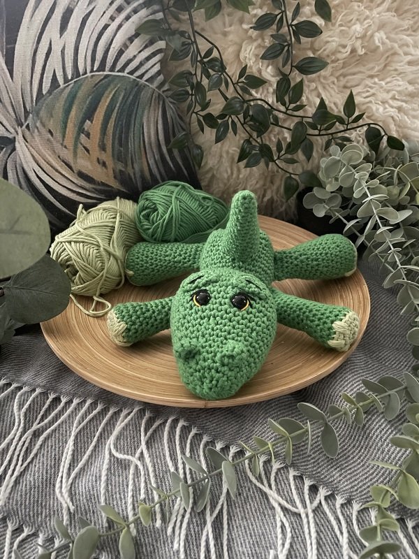 Grünes gehäkeltes Krokodil Amigurumi auf Holzschale mit Garnknäueln