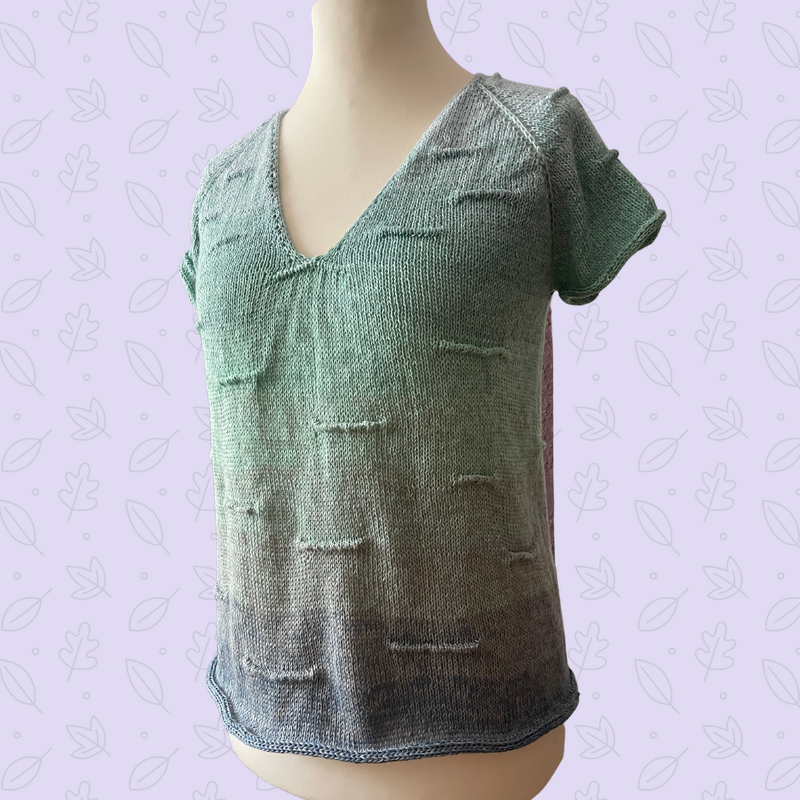 Gestricktes Damenshirt in Grün-Blau-Farbverlauf mit V-Ausschnitt und kurzen Ärmeln auf einer Schneiderpuppe